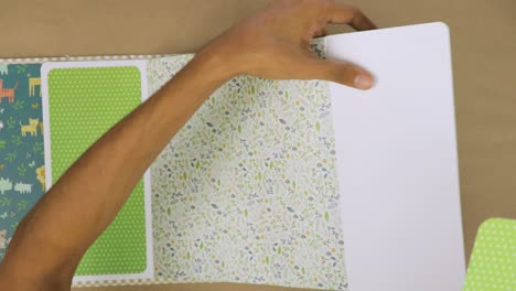 crafting colorful baby scrapbook album with glue and patterned papers, top-down view, close-up