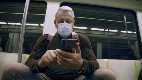 un anciano con una máscara protectora viaja en el metro