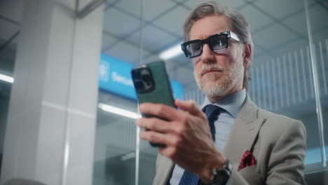 older man using smartphone in train station