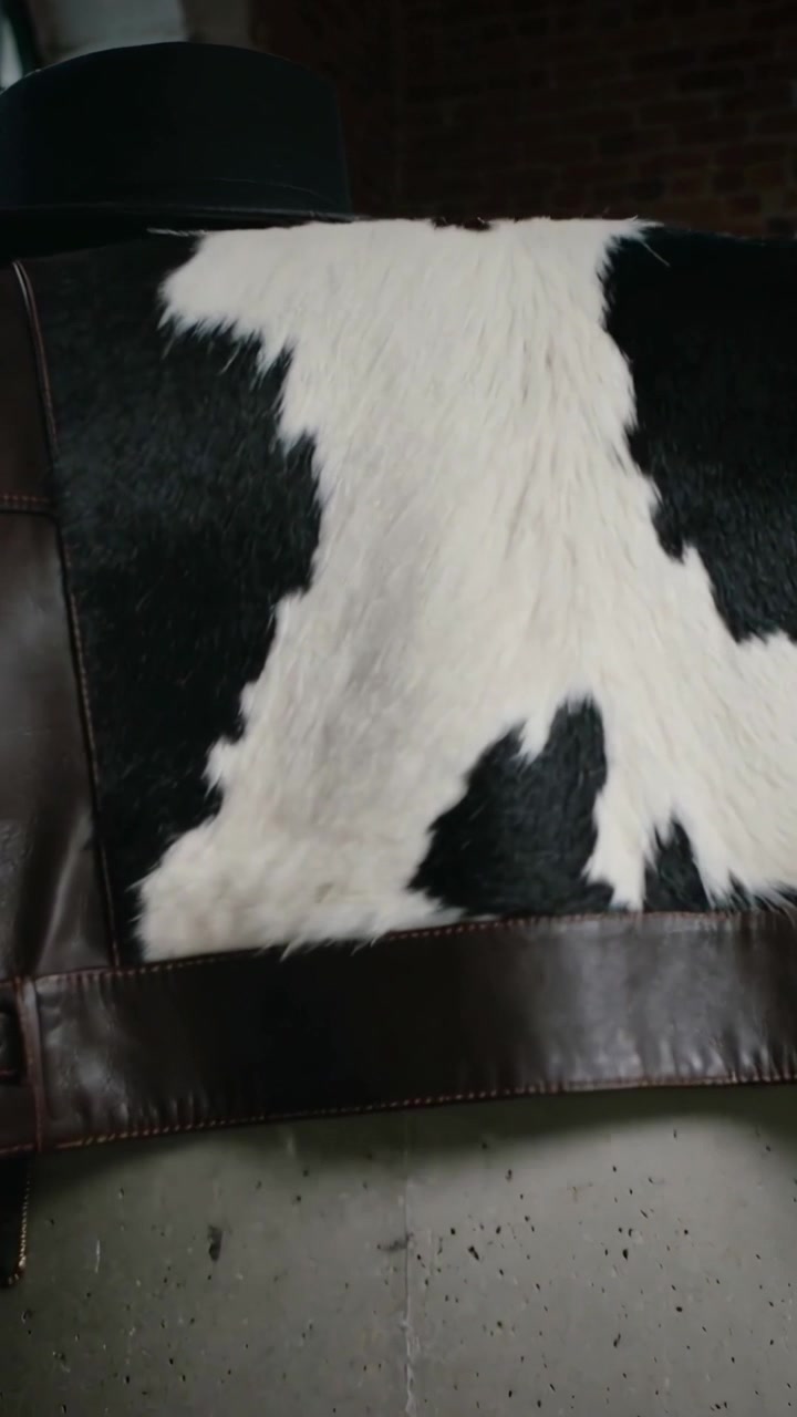 Video verticale: Telecamera in movimento che mostra una pelle di mucca sopra una giacca su una sedia in studio, rivelando dettagli della pelliccia