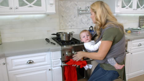 Busy-Mother-With-Baby-In-Sling-At-Home