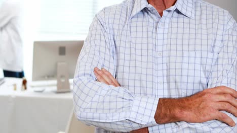 portrait of senior man standing with arms crossed