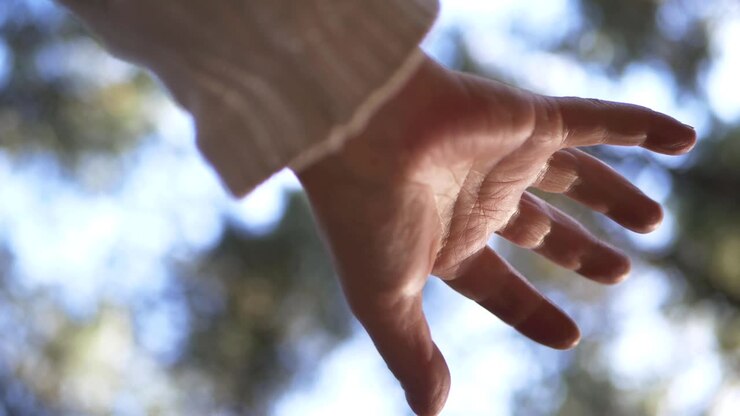 Eén hand die uitreikt tegen een achtergrond van bokeh-lichten, medium shot