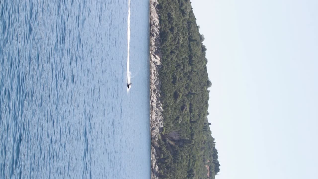 Jet ski racing in the crystal clear Adriatic Sea with the Otok Lokrum island in the background in Dubrovnik, Croatia