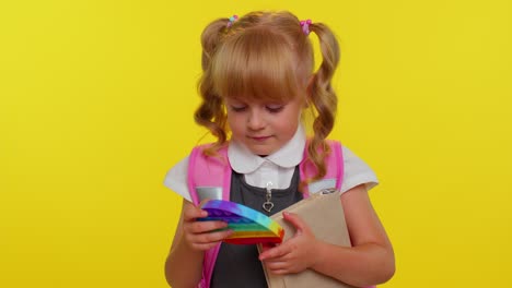 Funny-pupil-girl-playing-with-pop-it-sensory-anti-stress-toy-kid-presses-on-colorful-squishy-bubbles