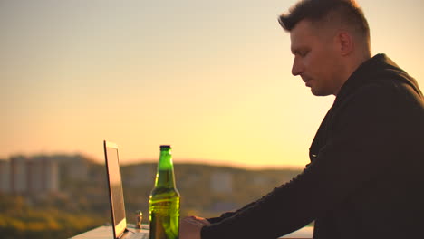 Hipster-man-with-a-laptop-on-the-edge-of-the-roof.-Freelancer-at-work.-Wireless-mobile-Internet.-He-works-on-the-Internet.