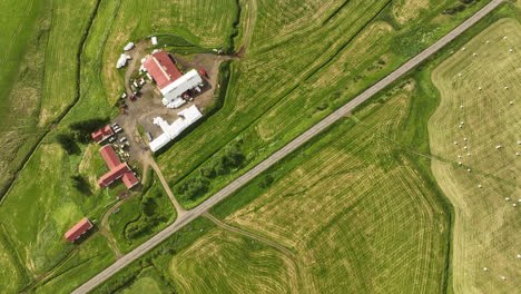 top shot aerial over a road with green fields and a farmer house in iceland