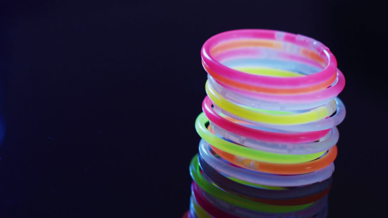 다채로운 네온 빛의 스틱과 검은색 배경의 빛의 반점의 애니메이션