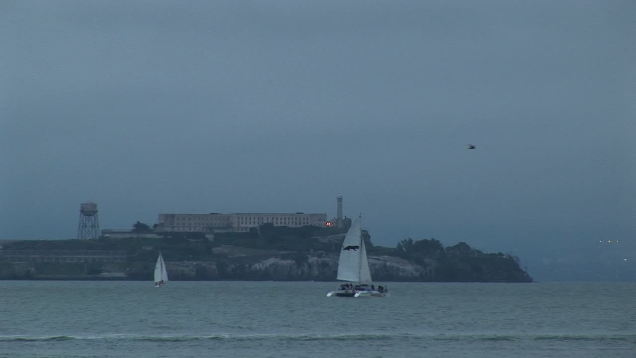 샌프란시스코 맞은편에 있는 역사적인 알카트라즈 섬을 지나 이동하는 쌍동선의 중간 샷