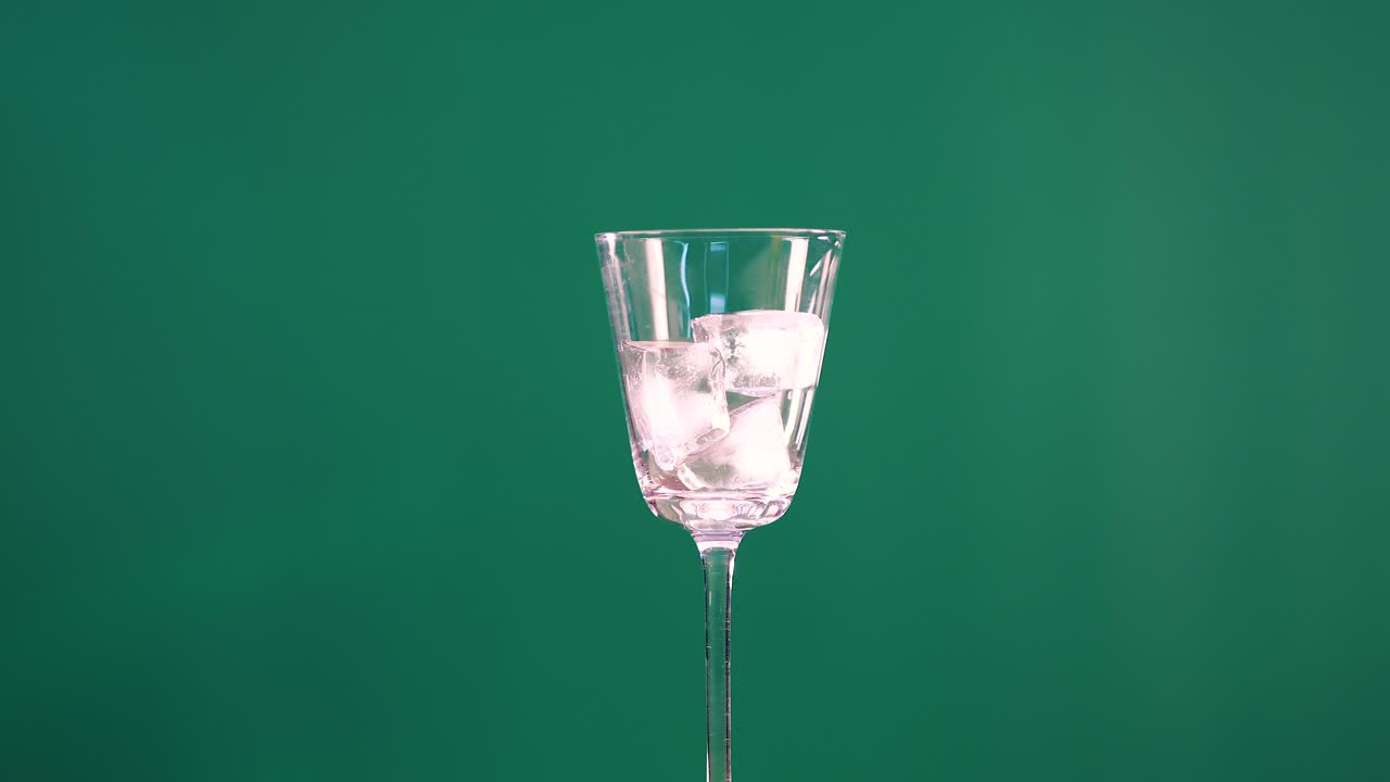 A cocktail glass with ice rotates against a green screen backdrop, showcasing smooth motion and clear lighting
