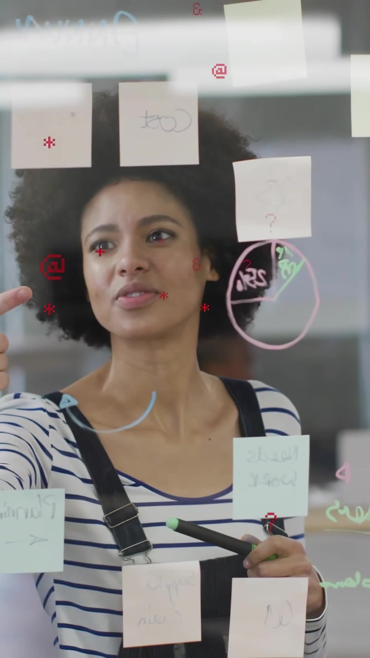 Video vertical: Colega señalando un gráfico circular, guiando al líder que coloca notas en un cristal, planificando con un marcador verde.