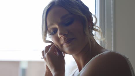 bride puts her wedding earrings in