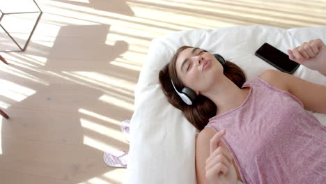 caucasian young woman lying down, listening to music, copy space