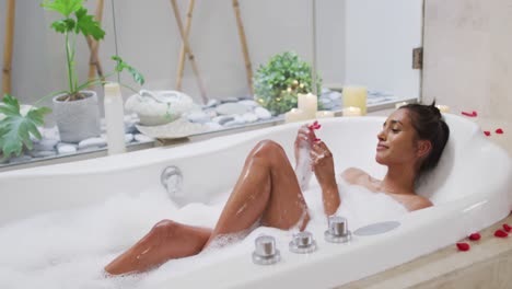 Mixed-race-woman-lying-in-a-bathtub-at-home