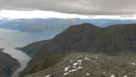 Pan-of-an-Epic-Rocky,-Barren,-High-Altitude-Landscape-to-A-Vibrant-Fjord-in-Norway