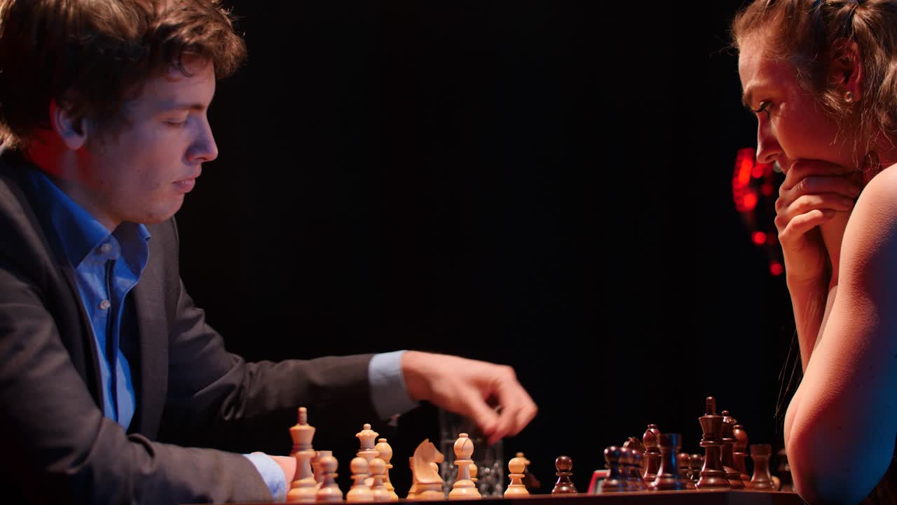 el hombre captura el peón central en un partido de ajedrez con poca luz contra una oponente femenina.