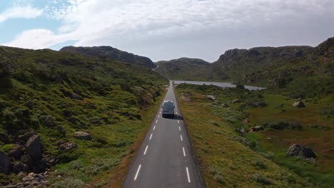 long, empty road in norway with mountains, sky, and a camper van driving