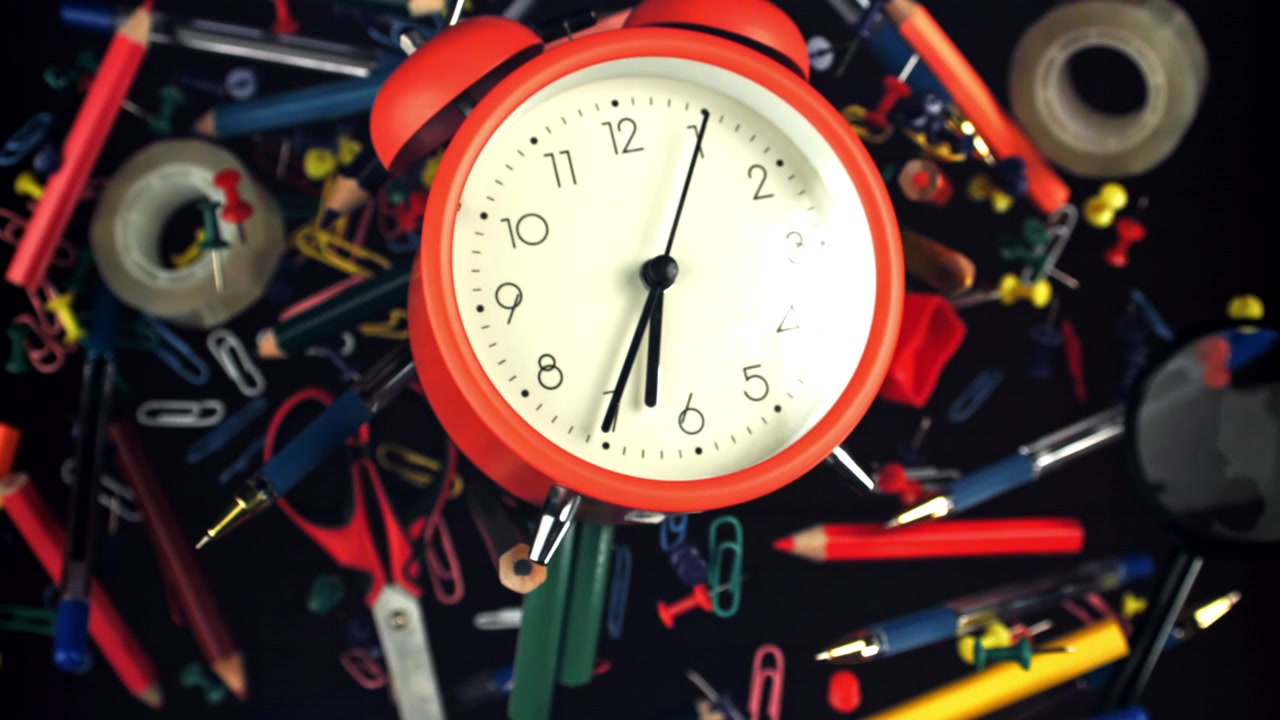 Red Alarm Clock Surrounded by Colorful Office Supplies