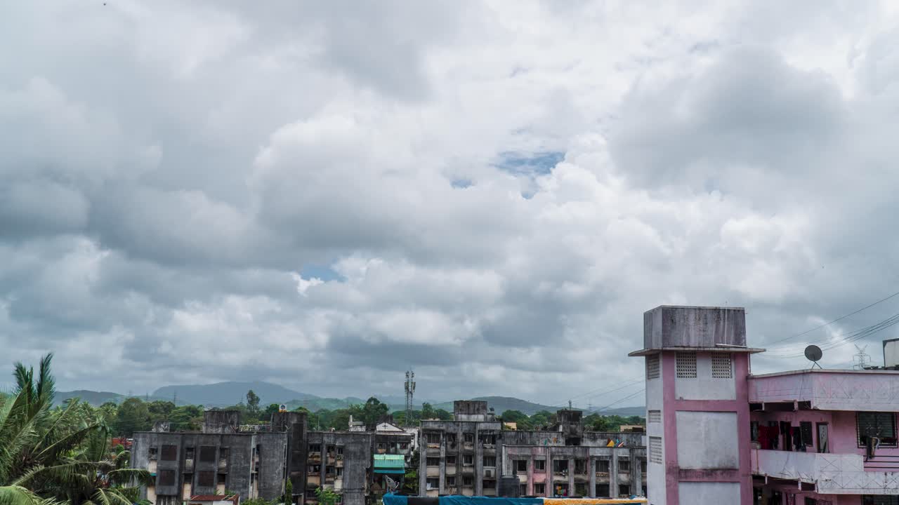 suburbio de la ciudad pequeña de lapso de tiempo, nubes moviéndose rápido, capas de montaña en la distancia