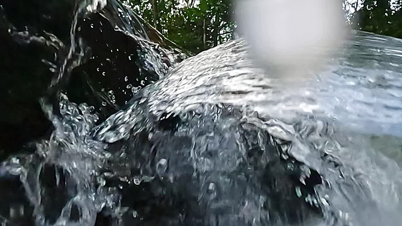 Rapid water surges and splashes in a lush forest cascade