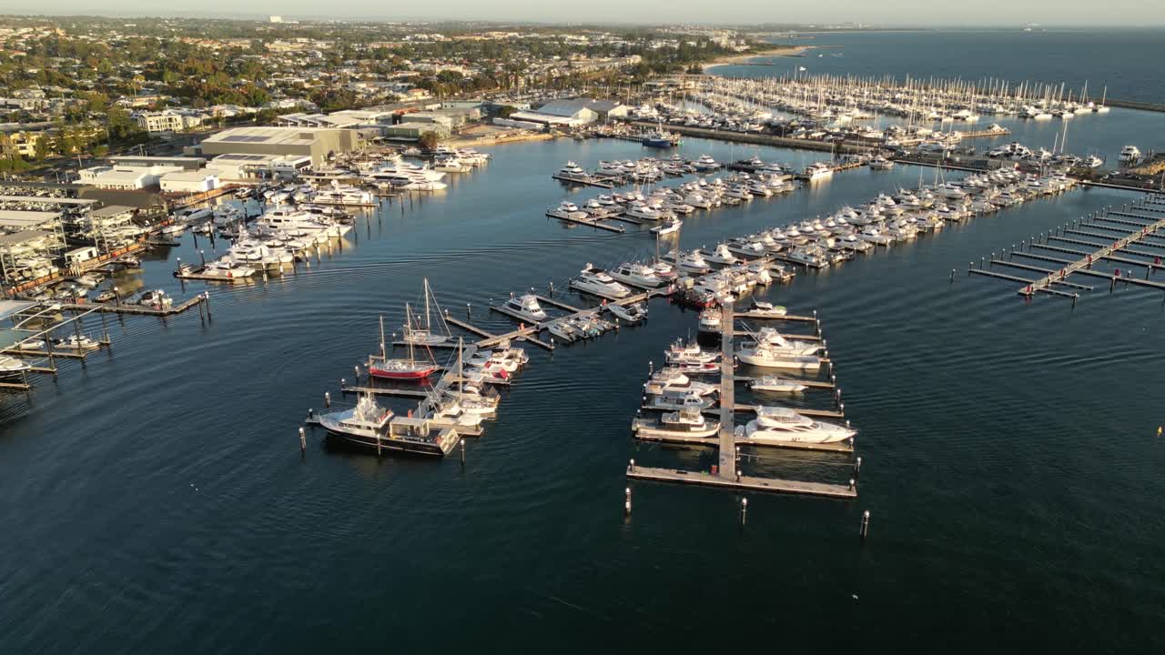 Aerial establishing shot of Fremantle Sailing Club in Perth City and arriving boat at sunset, Western Australia - drone forward flight