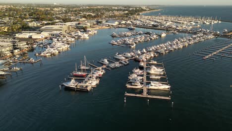 aerial establishing shot of fremantle sailing club in perth city and arriving boat at sunset, western australia - drone forward flight