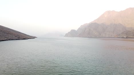 Aerial-shot-of-rocky-desert-mountains-and-sea-in-Musandam,-Oman