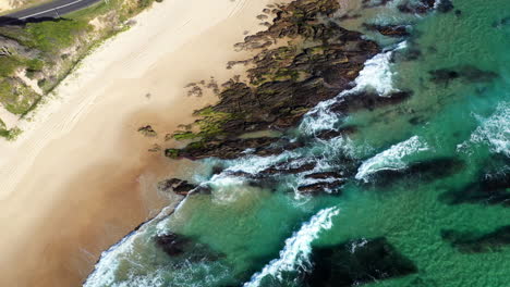 Rising-cinematic-drone-shot-of-Shelly-Beach-and-the-Wellington-Rocks-with-coastal-highway-and-ocean-waves-at-Nambucca-Heads-New-South-Wales-Australia