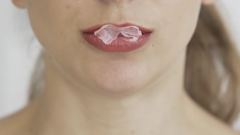 close up of blonde caucasian young girl with red lips chewing gum and blowing bubbles , hipster pop footage,b roll two