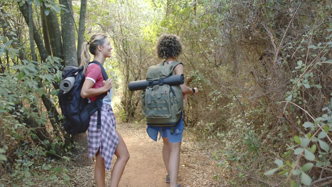 Video verticale: Vibrazioni che irrompono nell'inquadratura, mostrando due donne che sistemano gli zaini e un sentiero escursionistico per un viaggio.