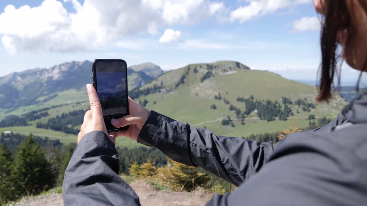 niña tomando fotos panorámicas del hermoso paisaje montañoso en suiza durante el día soleado y ventoso