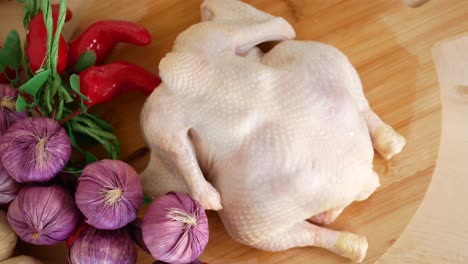 whole raw chicken on cutting board with peppers and onions