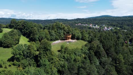 An-orbit-drone-captures-a-wooden-viewpoint-structure-perched-on-a-hill,-offering-a-breathtaking-aerial-perspective-of-a-tranquil-lakeside-scene