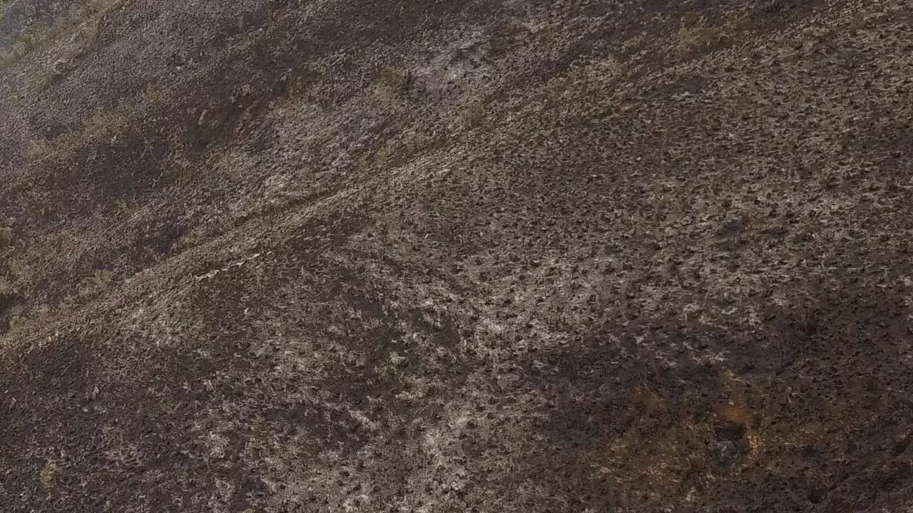 plano aéreo cercano de ángulo bajo de fuego terreno montañoso quemado, brasil