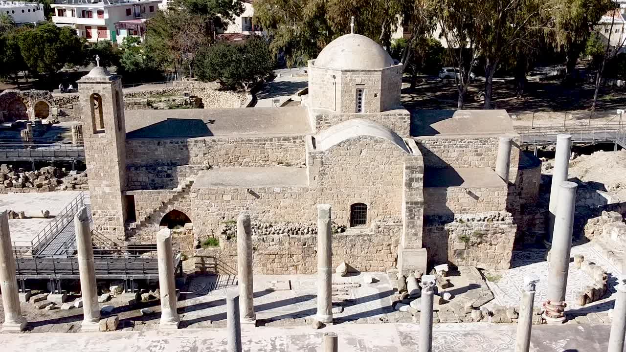 Visitors wander through ancient ruins in Cyprus, admiring well-preserved mosaics and exploring the rich history of the site. Discover the beauty of this archaeological treasure