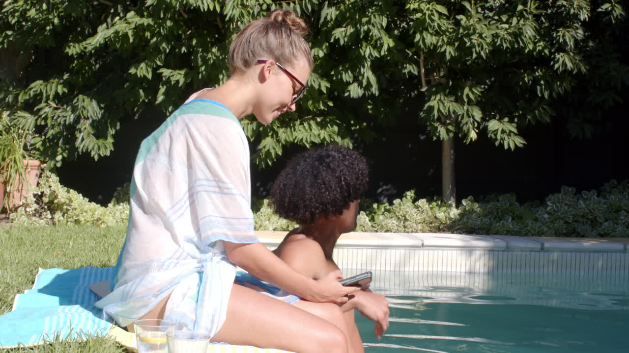 Diverse couple relaxing by pool, enjoying drinks and sunshine on summer day, copy space