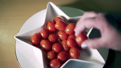 tomatoes in shaped star dish with old woman hand taking one delicately