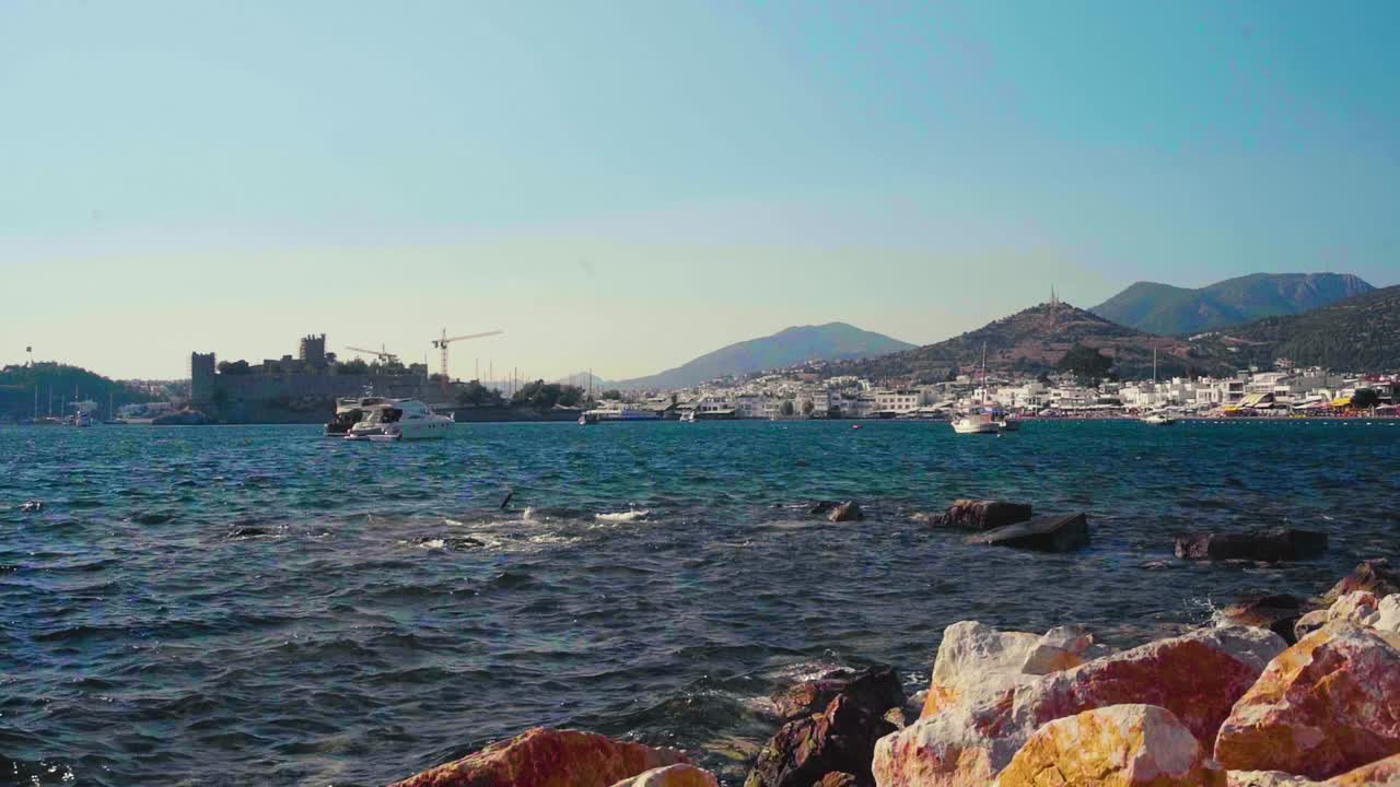View over ships at the Mediterranian coast, in the background lies the historical castle 'Bodrum Kalesi' in Bodrum, Turkey