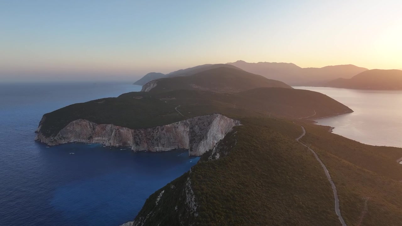 Veduta aerea di ripide scogliere bianche e mare blu illuminati dalla luce dell'alba lungo la cresta di una penisola costiera