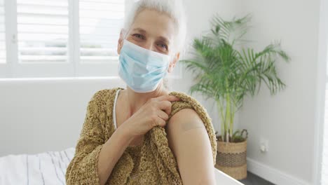 caucasian senior woman wearing face mask and plaster after vaccination