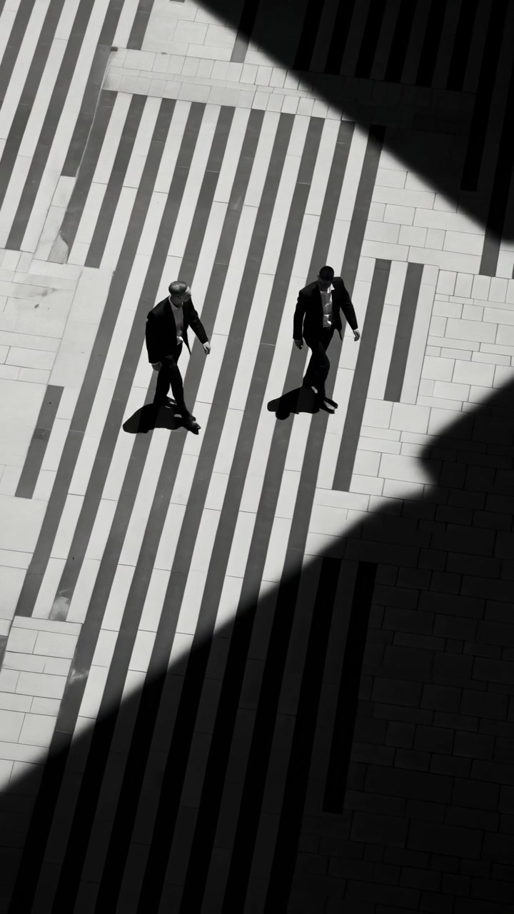 Overhead View of Two Men in Suits Walking Through Striped Shadows