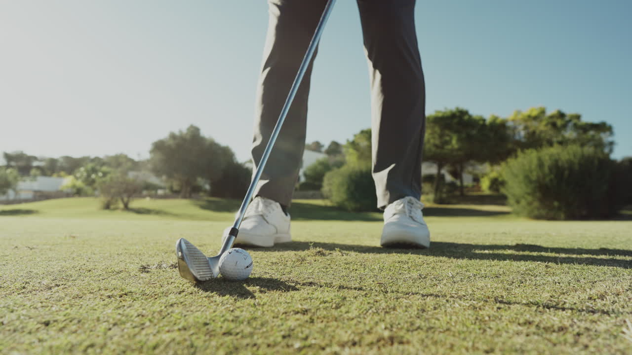 Primo piano da un'angolazione inferiore di un giocatore di golf che si prepara a tirare su un campo curato, che mostra concentrazione, precisione e azione sportiva all'aperto durante una giornata luminosa e limpida