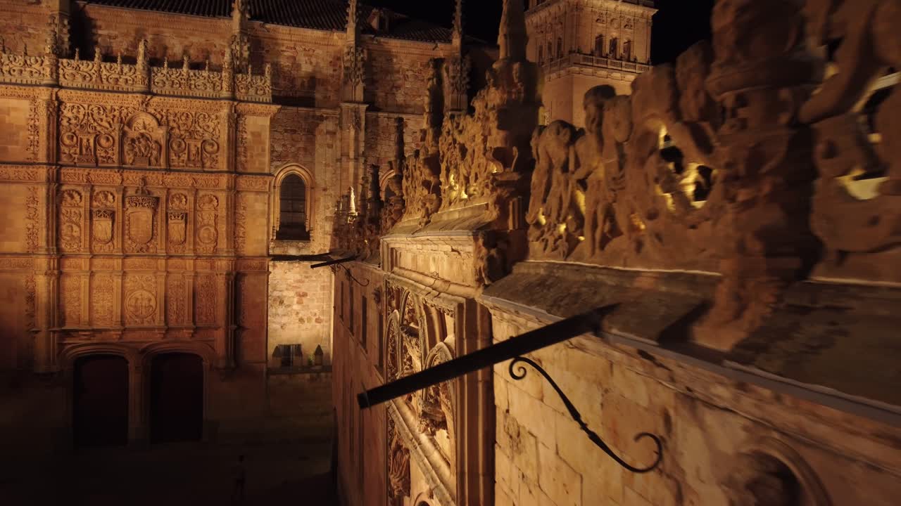 siguiendo el borde de la fachada de un edificio de patrimonio neoclásico en salamanca, españa, a corta distancia, iluminado por la noche