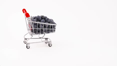 el carrito de compras con arándanos frescos se mueve hacia adelante. aislado en el fondo blanco. primer plano. macro.