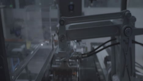 automated vaccine vial on conveyor belt by modern robot hand, the capping and labeling of injections at a biopharmaceutical company production line