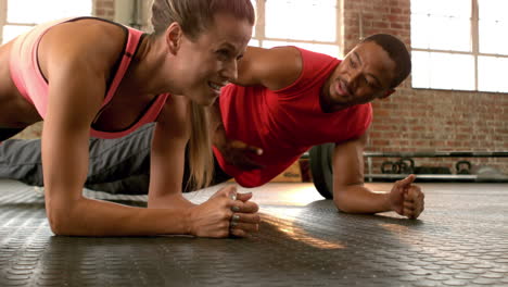 Fit-couple-planking-together-in-gym-