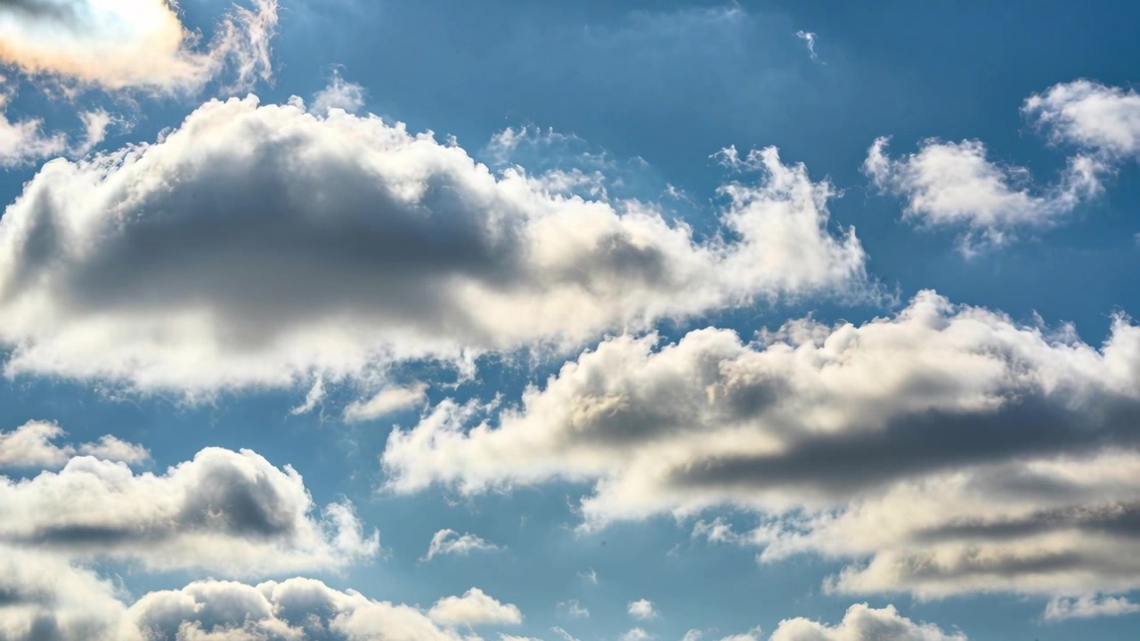 Drifting big main cumulus cloud thinning, revealing blue sky, pushed by light breeze with long bank