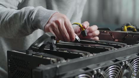 close up of man's hands connect the power cords of mining rig for mining cryptocurrency