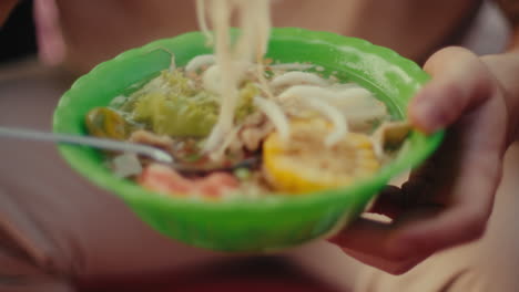 handheld bowl of vietnamese noodles
