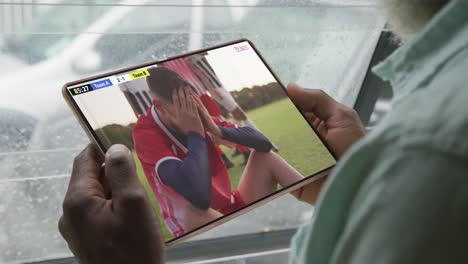 Video-of-person-sitting-on-the-couch-and-watching-football-match-on-tablet